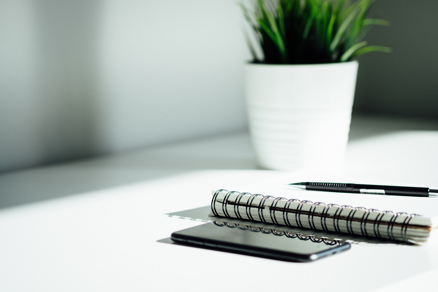 Notizbuch, Stift und Smartphone auf einem hellen Schreibtisch
